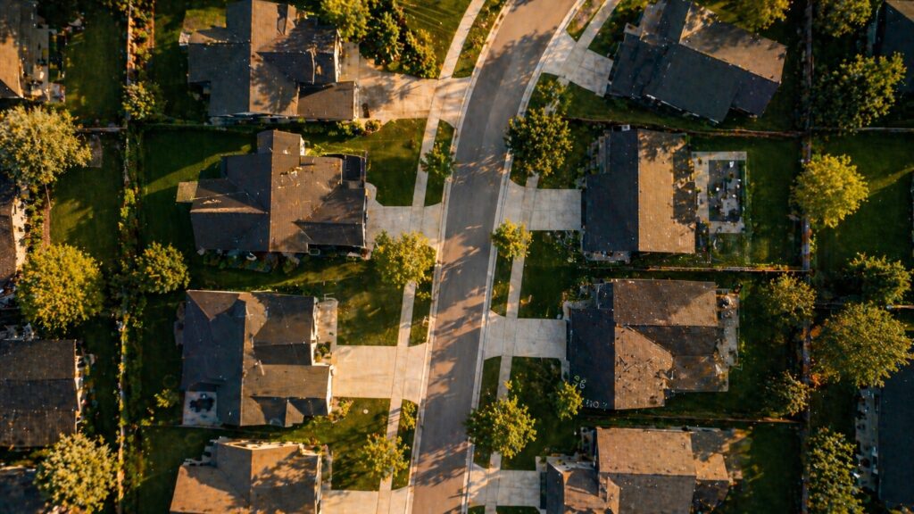 Aerial view of a modern suburban neighborhood at golden hour — illustrating the bigger-picture timing question of whether refinancing is worth it if moving